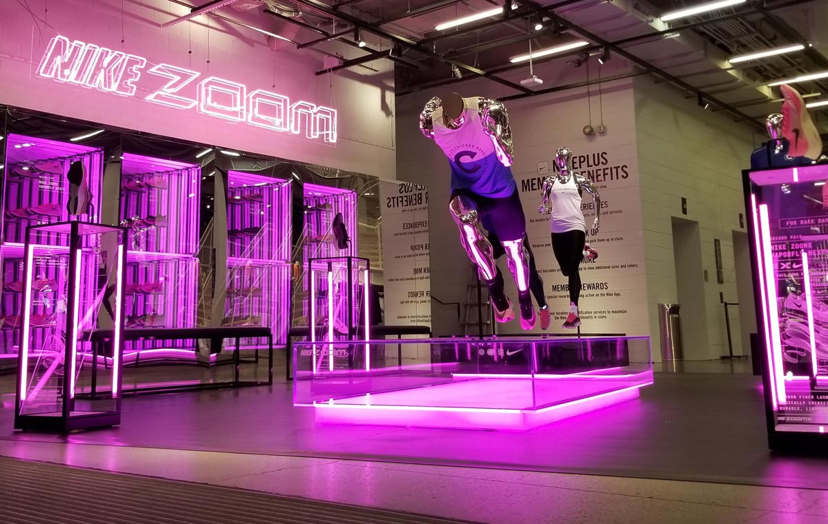 A bold Nike interior with neon pink and purple accents exemplifies an experiential retail activation