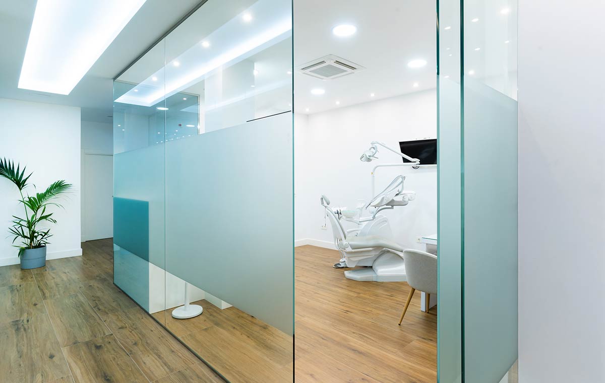 An etched glass wall with an open door to a medical and healthcare office showcases modern interior design.