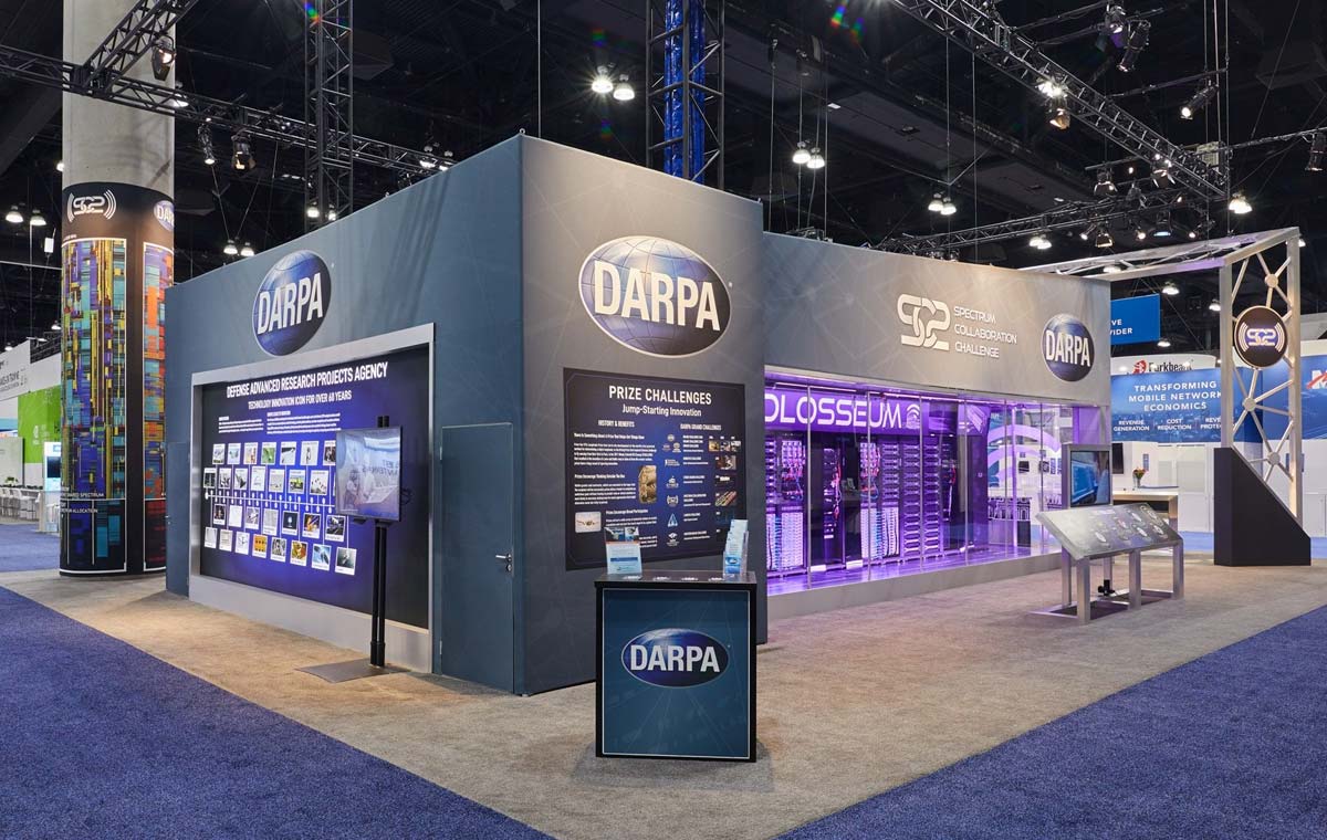 Image of navy blue DARPA trade show booth in a large event space