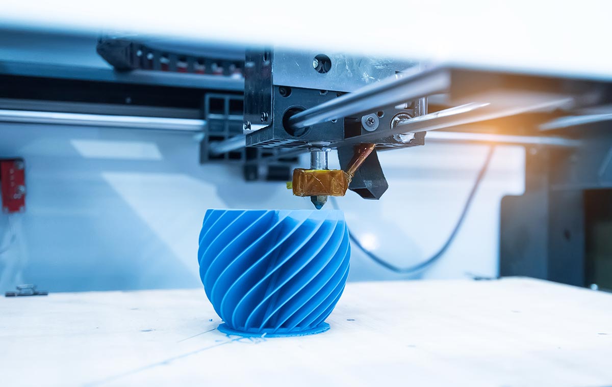 A 3D printer fashions a blue mold on a white surface