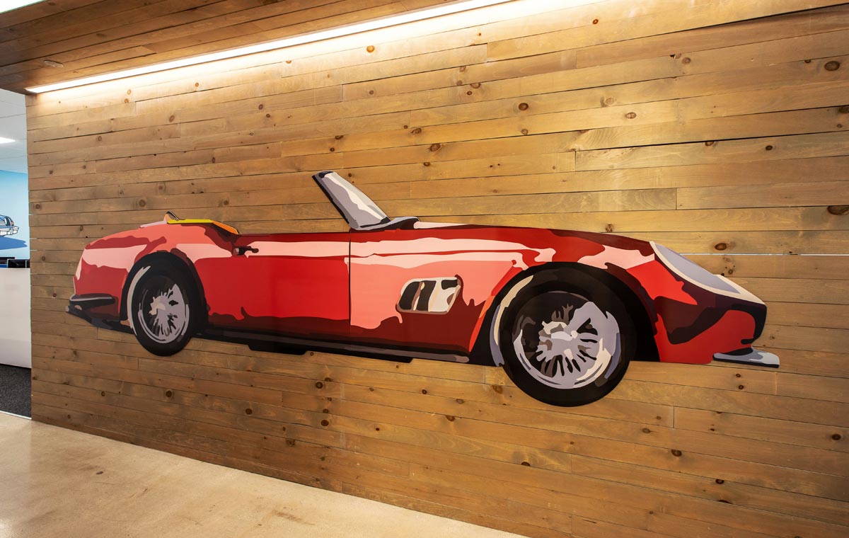 A sleek red sports car adorns the wall of a commercial office representing environmental graphic design for brand experiences