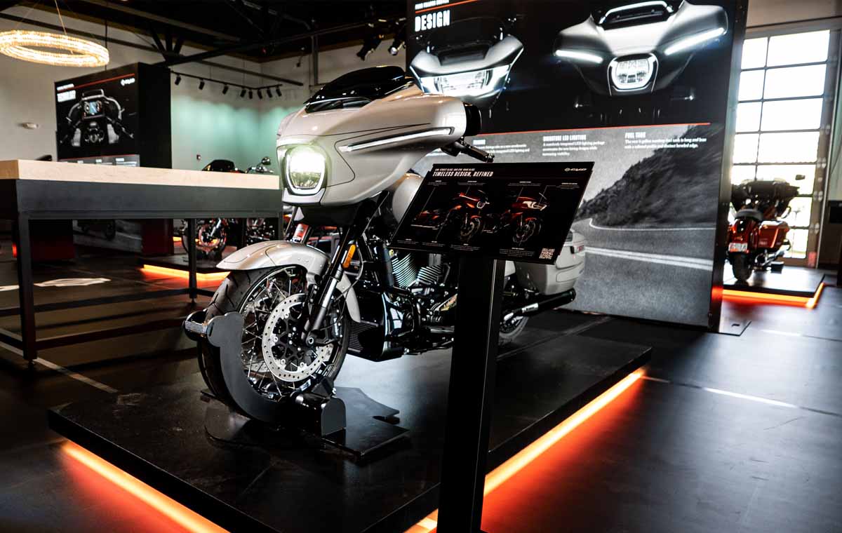 A white Harley-Davidson motorcycle on a raised platform in an immersive retail space