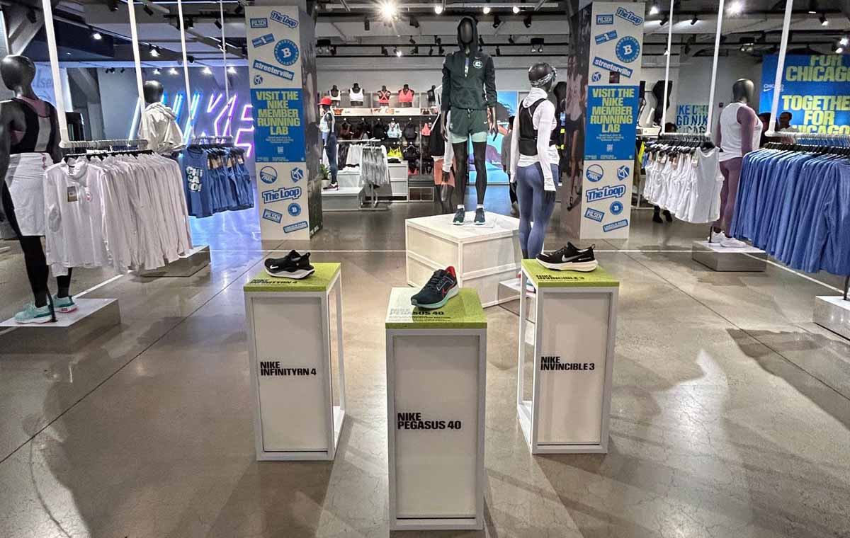 A spacious Nike retail environment with white pedestals showcasing sneakers and clothing