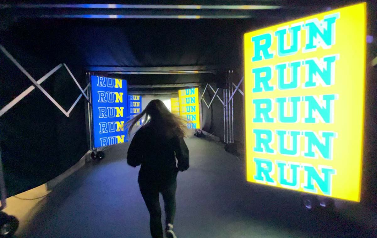 a woman runs through an immersive entertainment activation at SoFi Stadium