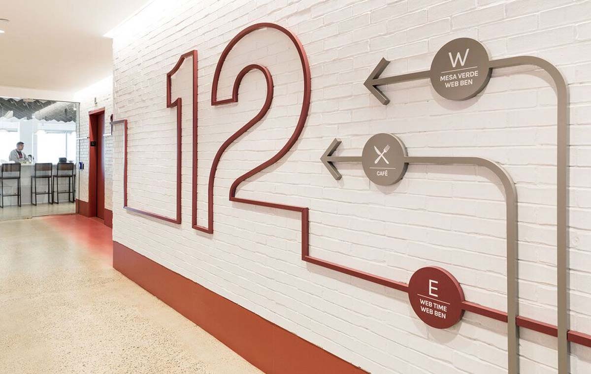 A red tubular number 12 adorns a brick hallway along with other wayfinding graphics